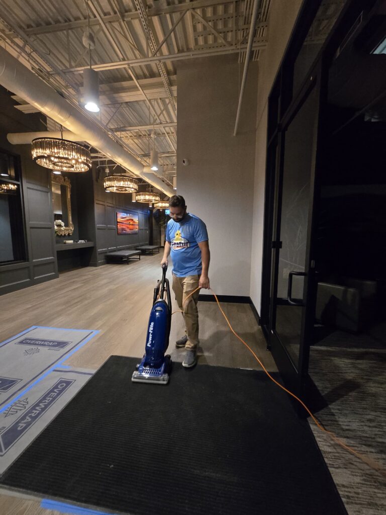 Gleeful tam member vacuuming an office building